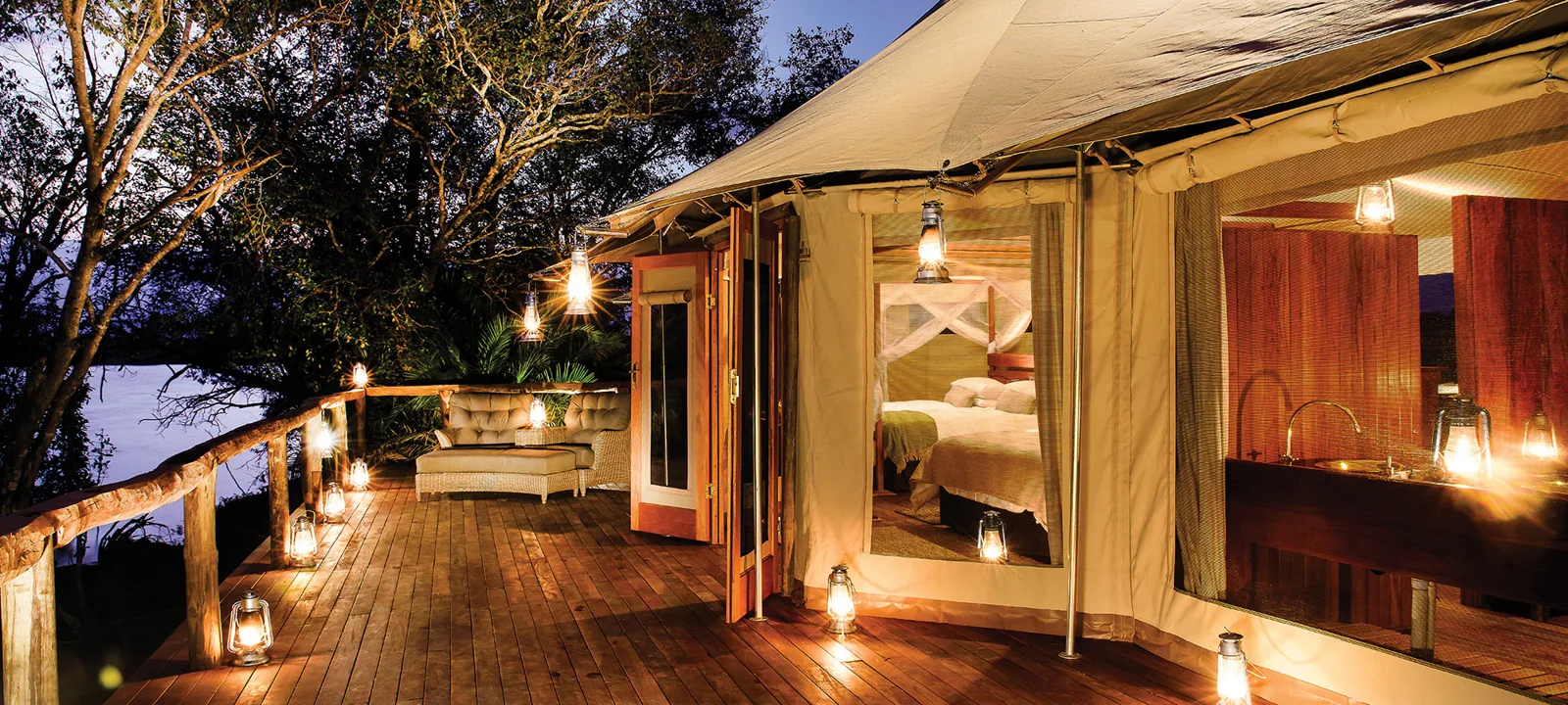 Riverside tent lit at dusk on the Kafue River, Kafue National Park, Zambia