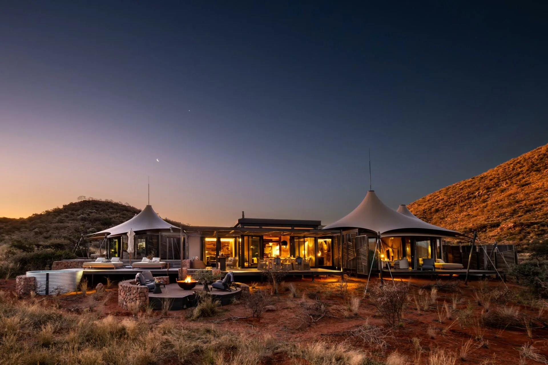 Loapi Tented Camp lit at dusk below the Korannaberg, Tswalu Kalahari Reserve