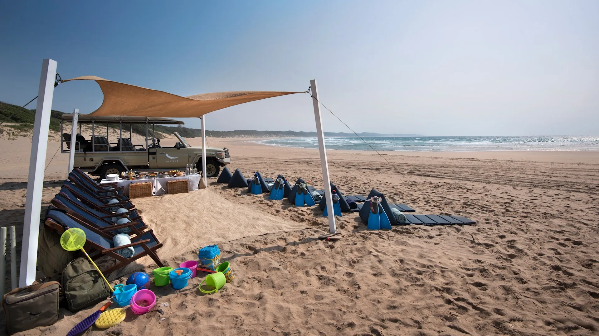 Beach set-up with shade sail, loungers and a game viewing vehicle on the sand at Sodwana Bay, KwaZulu-Natal