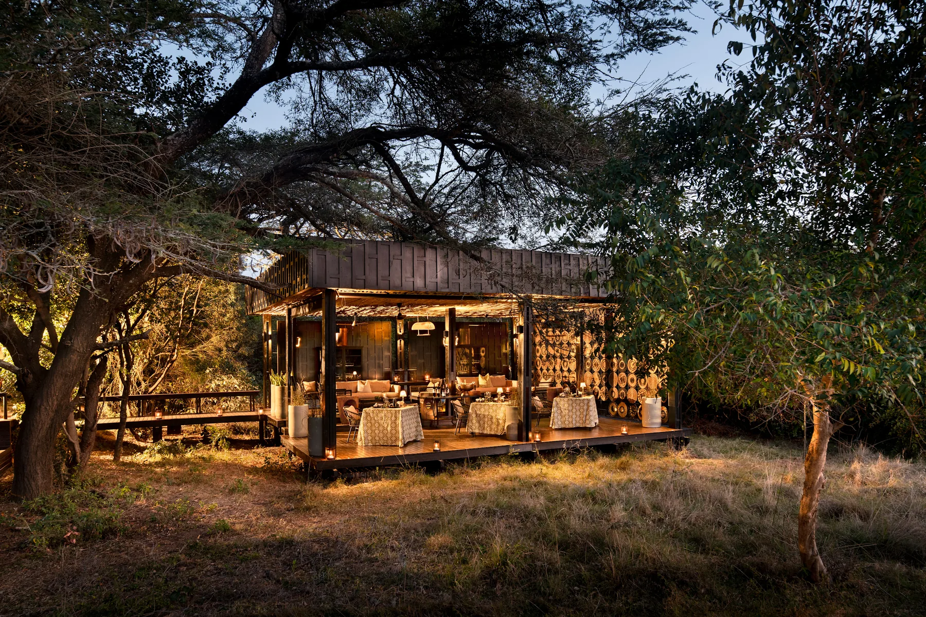 Dining pavilion lit by lantern under fever trees at dusk, andBeyond Phinda Vlei Lodge, KwaZulu-Natal